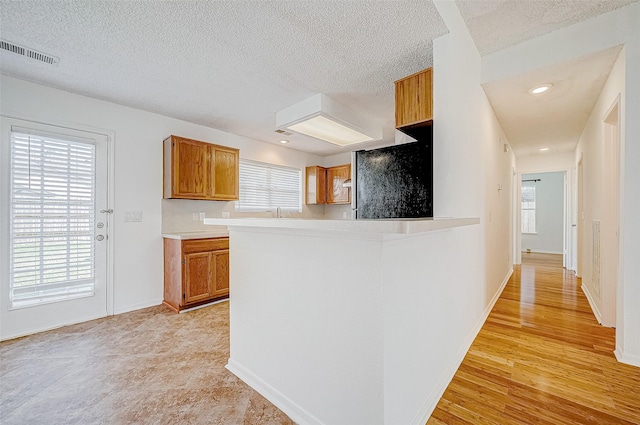 kitchen with a textured ceiling, kitchen peninsula, and stainless steel refrigerator