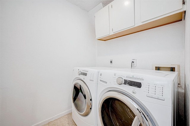 laundry area featuring a textured ceiling, cabinets, light tile patterned floors, and independent washer and dryer