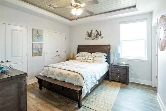 bedroom with a raised ceiling, ceiling fan, wood ceiling, and hardwood / wood-style floors