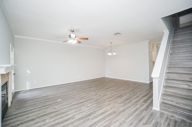 unfurnished living room with ceiling fan with notable chandelier, ornamental molding, and hardwood / wood-style floors