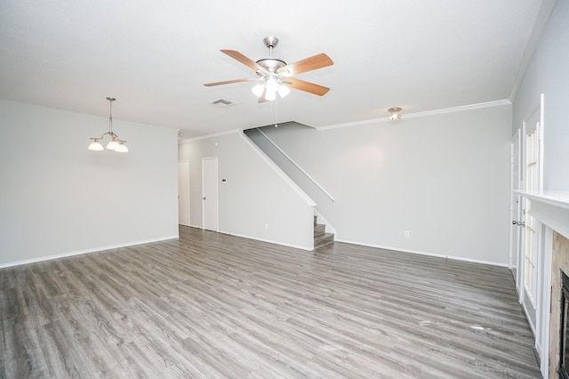 unfurnished living room featuring ceiling fan with notable chandelier, crown molding, and wood-type flooring