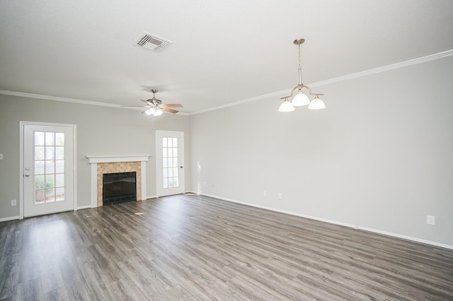 unfurnished living room with ceiling fan with notable chandelier, a tile fireplace, ornamental molding, and hardwood / wood-style flooring