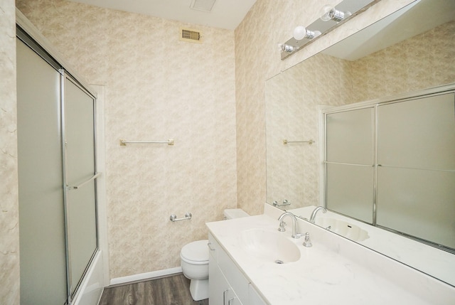 full bathroom featuring hardwood / wood-style floors, shower / bath combination with glass door, vanity, and toilet