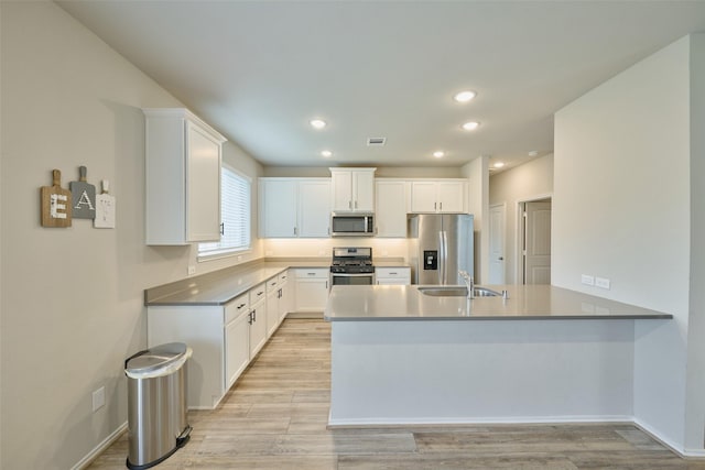 kitchen with sink, kitchen peninsula, appliances with stainless steel finishes, and white cabinetry