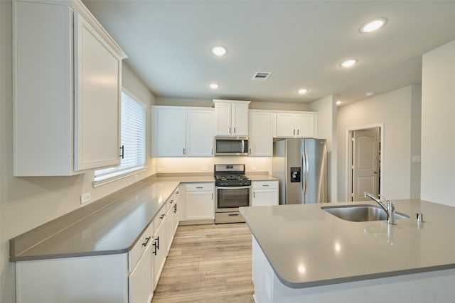 kitchen with sink, white cabinets, light hardwood / wood-style floors, and appliances with stainless steel finishes