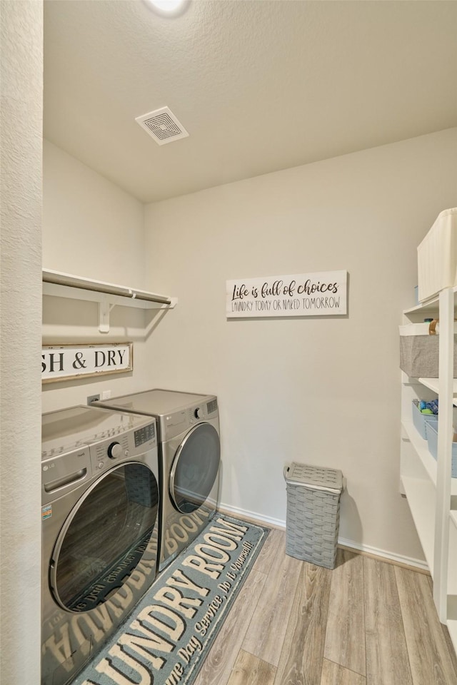 clothes washing area with light wood-type flooring and washing machine and clothes dryer