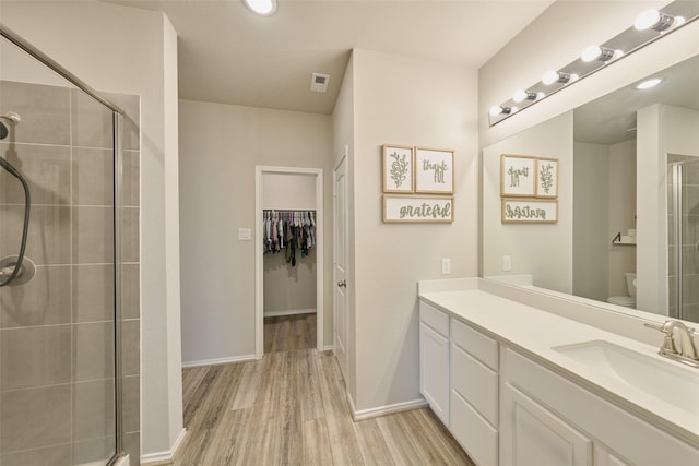 bathroom featuring toilet, vanity, a shower with shower door, and hardwood / wood-style floors