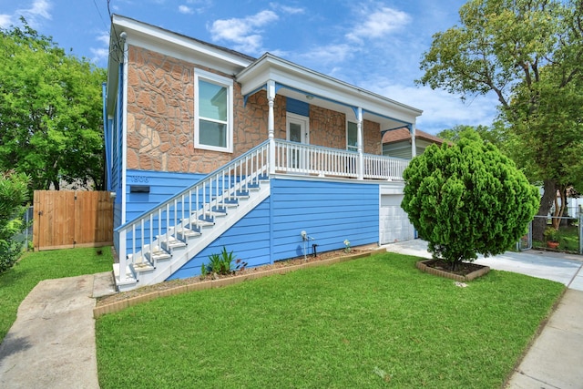 view of front of home featuring a porch, a front yard, and a garage