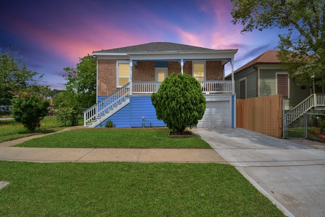 view of front of property with a porch, a lawn, and a garage