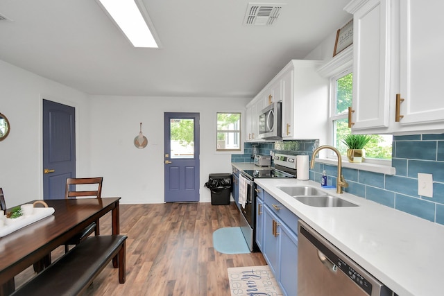 kitchen with stainless steel appliances, sink, white cabinets, decorative backsplash, and dark wood-type flooring