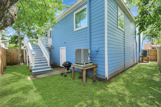 rear view of property featuring central air condition unit, a deck, and a yard