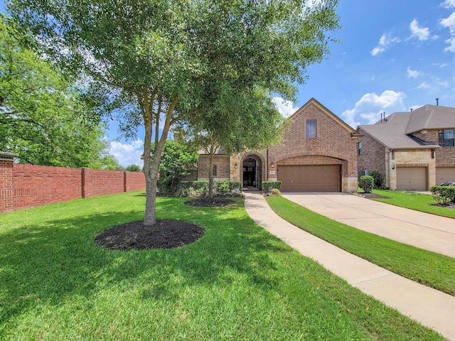 view of front facade with driveway, a front yard, a garage, brick siding, and fence