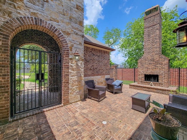 view of patio with a gate, an outdoor living space with a fireplace, and fence