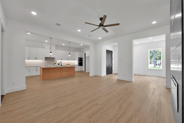 kitchen featuring light hardwood / wood-style flooring, pendant lighting, a spacious island, tasteful backsplash, and white cabinetry