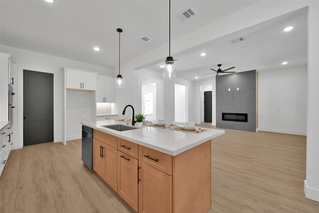 kitchen featuring light stone countertops, dishwasher, an island with sink, white cabinets, and sink