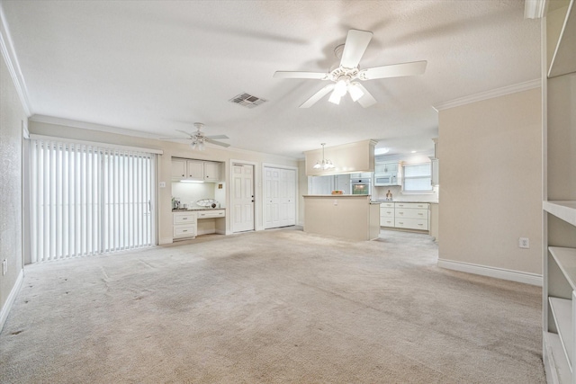 unfurnished living room with plenty of natural light, ceiling fan with notable chandelier, and ornamental molding