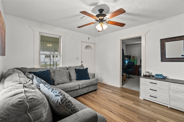 living room featuring ceiling fan, a textured ceiling, and hardwood / wood-style flooring