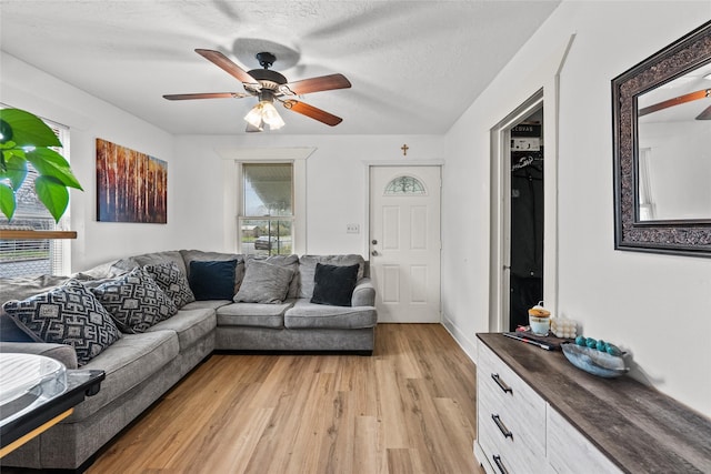 living room featuring light wood-type flooring, a textured ceiling, and ceiling fan