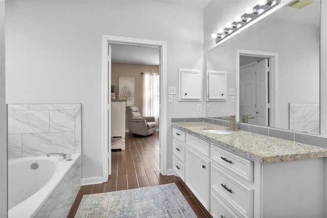 bathroom featuring vanity and tiled bath