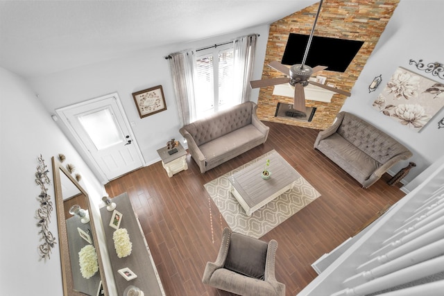 living room with lofted ceiling, hardwood / wood-style floors, ceiling fan, and a stone fireplace