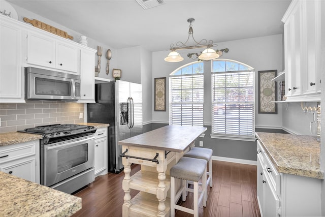 kitchen with white cabinets, stainless steel appliances, backsplash, and dark wood-type flooring