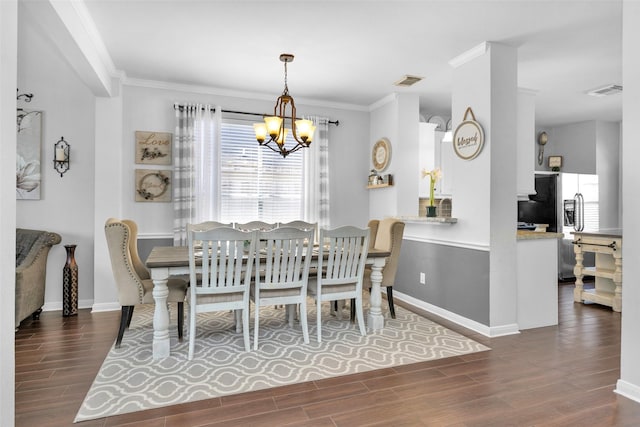 dining area featuring a chandelier, crown molding, and dark wood-type flooring