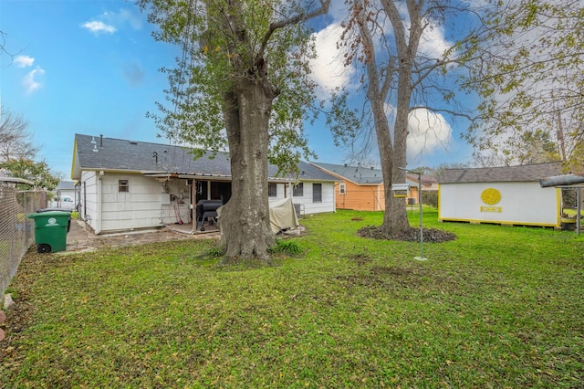 rear view of house featuring a lawn and a storage shed