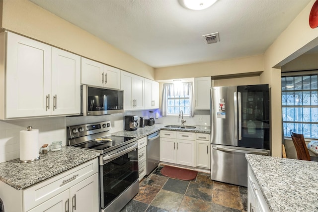 kitchen featuring white cabinets, appliances with stainless steel finishes, backsplash, and sink