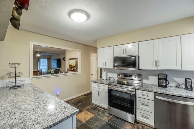 kitchen featuring white cabinetry, ceiling fan, tasteful backsplash, light stone countertops, and appliances with stainless steel finishes