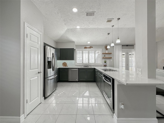 kitchen with stainless steel appliances, light stone countertops, kitchen peninsula, pendant lighting, and a textured ceiling