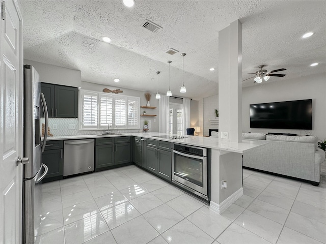 kitchen featuring stainless steel appliances, sink, ceiling fan, kitchen peninsula, and pendant lighting