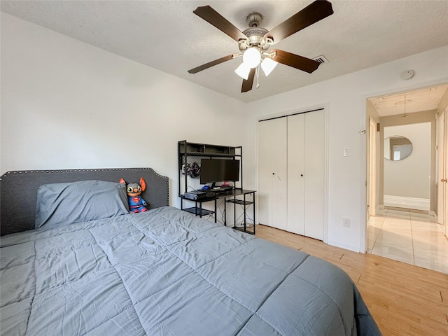 bedroom featuring hardwood / wood-style flooring, a textured ceiling, ceiling fan, and a closet