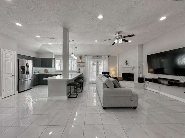 living room featuring a textured ceiling, a fireplace, ceiling fan, and vaulted ceiling