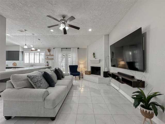 living room featuring a fireplace, ceiling fan, and a textured ceiling