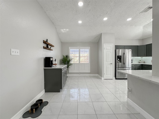 kitchen with stainless steel fridge with ice dispenser, light stone counters, a textured ceiling, lofted ceiling, and tasteful backsplash