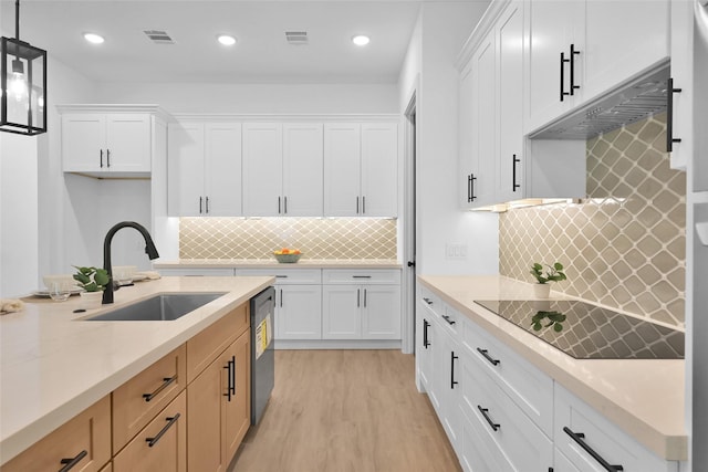 kitchen featuring sink, decorative light fixtures, white cabinetry, stainless steel dishwasher, and light stone countertops