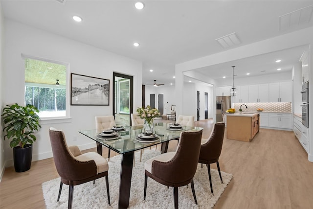 dining room with light wood-type flooring, ceiling fan, and sink