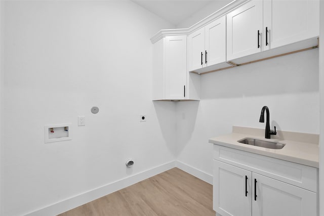 washroom with sink, hookup for a washing machine, cabinets, hookup for an electric dryer, and light wood-type flooring