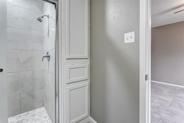 bathroom featuring a tile shower and ceiling fan