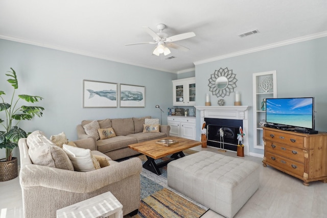 living room featuring ceiling fan, built in features, and crown molding