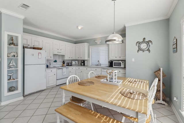 kitchen with white appliances, decorative light fixtures, light tile patterned floors, white cabinets, and sink