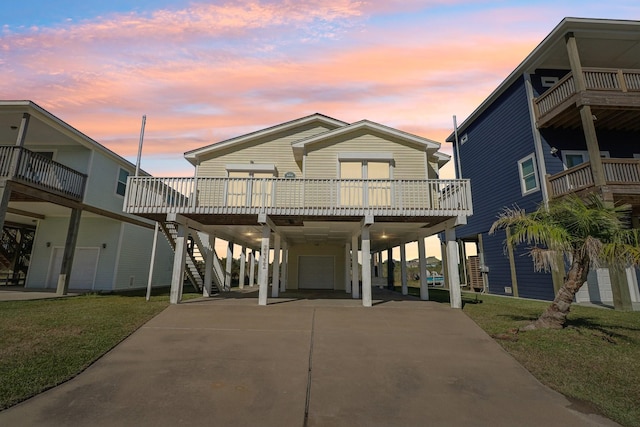 coastal inspired home with a balcony, a yard, and a carport