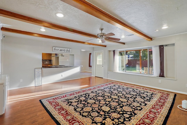 living room with a textured ceiling, ceiling fan, hardwood / wood-style floors, and beamed ceiling