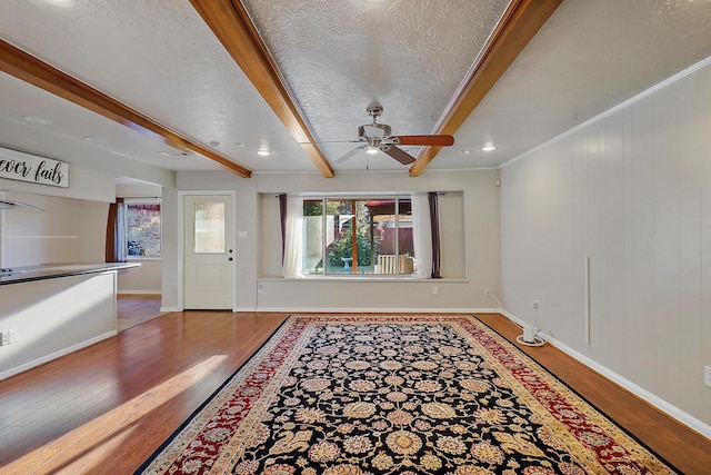 foyer entrance featuring a textured ceiling, ceiling fan, wood-type flooring, crown molding, and beam ceiling