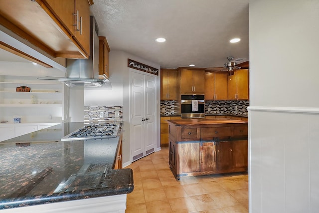 kitchen with dark stone countertops, appliances with stainless steel finishes, light tile patterned floors, ceiling fan, and decorative backsplash