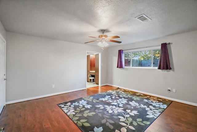 unfurnished bedroom featuring ceiling fan, ensuite bath, a textured ceiling, and hardwood / wood-style flooring