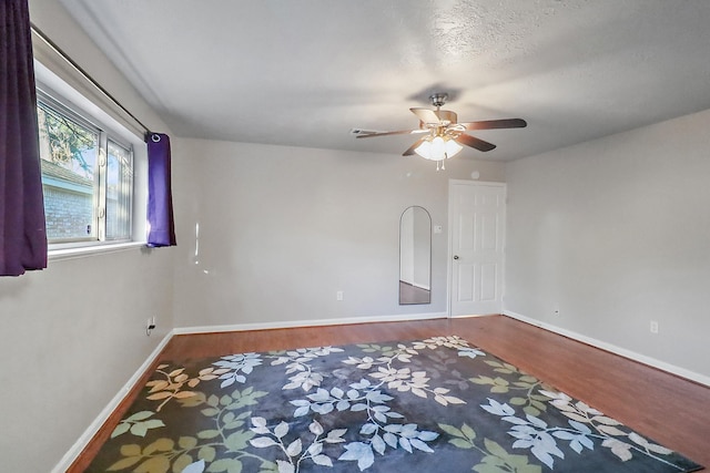 empty room featuring ceiling fan, a textured ceiling, and wood-type flooring