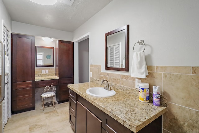 bathroom featuring tile walls, vanity, and a textured ceiling