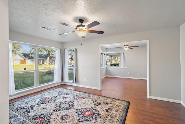 empty room featuring dark hardwood / wood-style flooring, a textured ceiling, and a healthy amount of sunlight