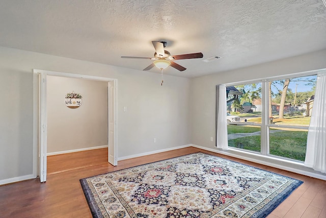 empty room featuring ceiling fan, hardwood / wood-style floors, and a textured ceiling